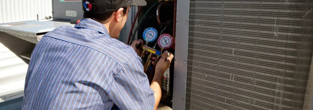 HVAC technician servicing a condenser unit in Columbia